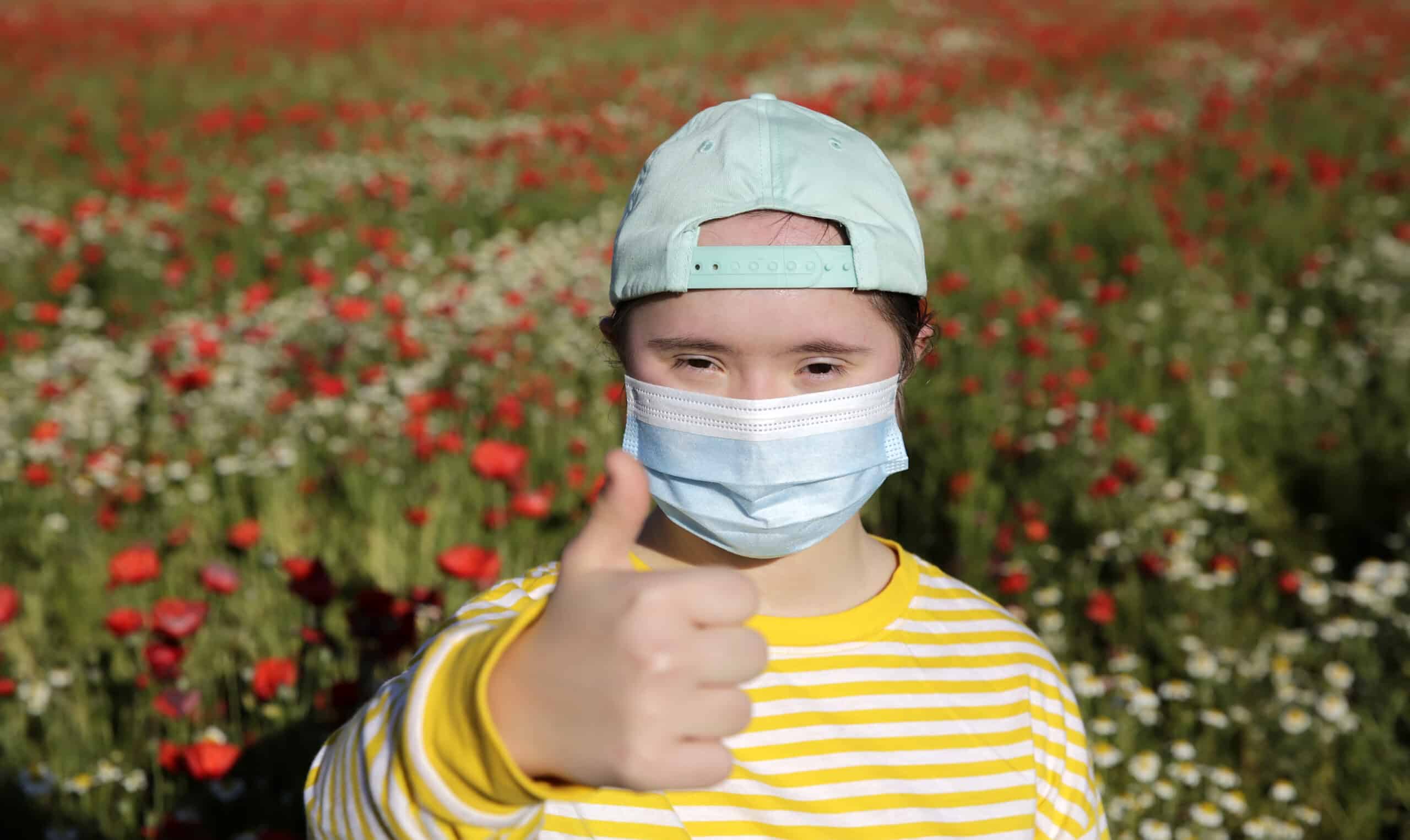 Girl with mask on the face on background on the flowers field