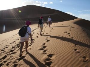 Morocco-snow-sand-erg-zaher-400x300 Three people walking across a sand dune in the desert.