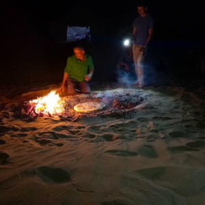Travel and Trek: Morocco Sahara Desert Bread Baking Courtesy of Travel & Trek, people in the Sahara desert baking bread by an open fire at night.