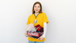 Woman holding a plastic box full of clothes to donate to charity.