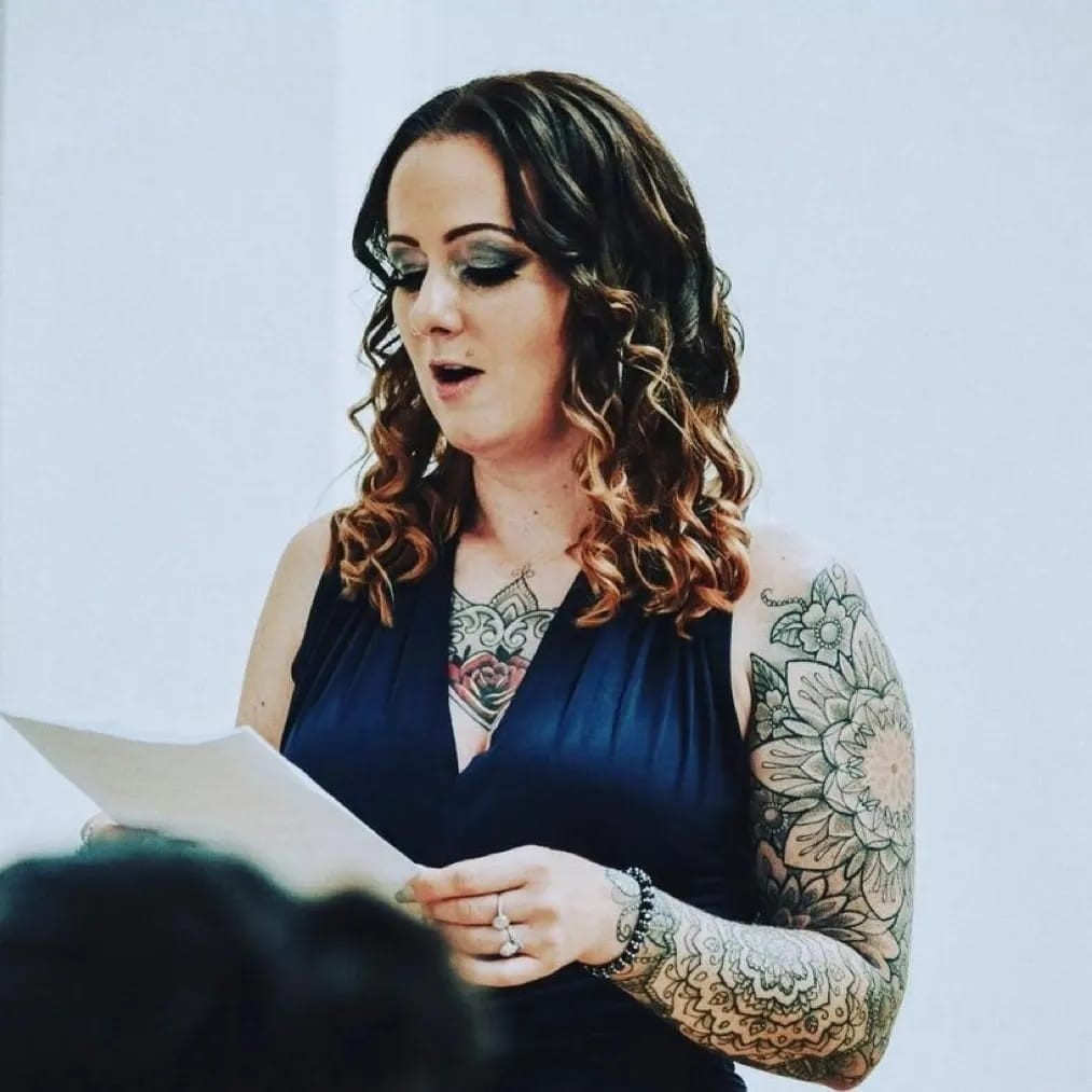 Amy Amy Hollinshead reading from a piece of paper to an audience