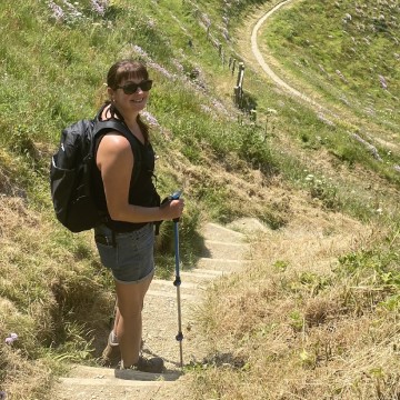 Woman hiking along hilly coastal track in the sun.