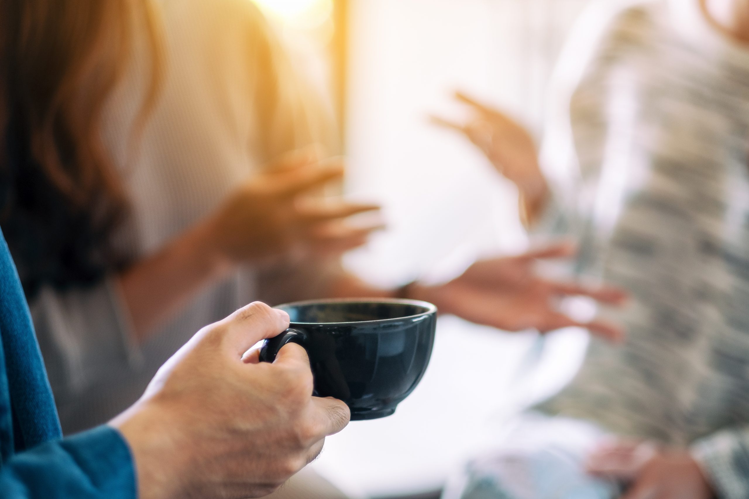 Close up image of people talking and drinking coffee together.