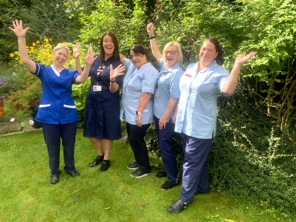 5 Katharine House Hospice nurses cheering with their arms in the air and smiling.