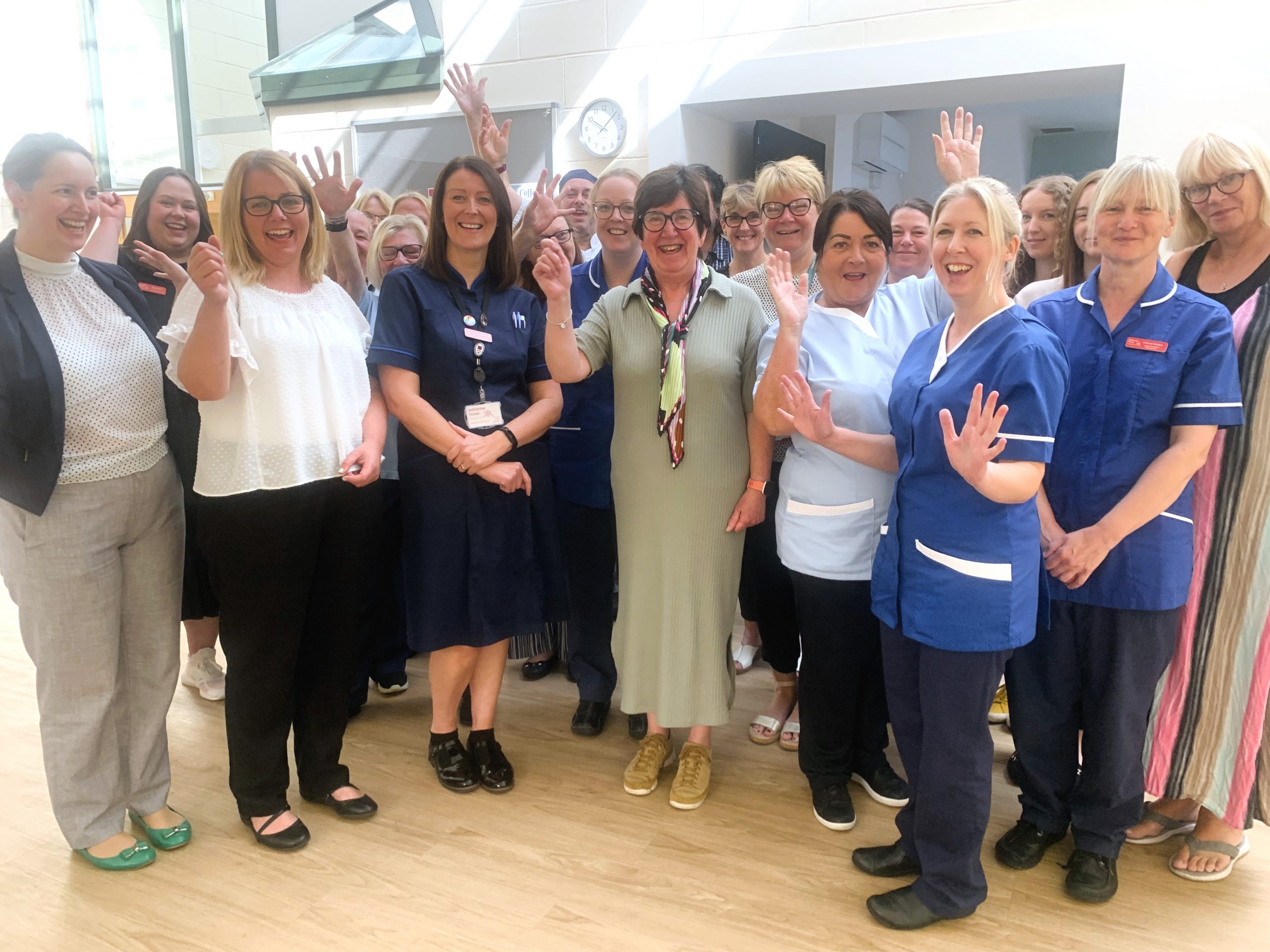 A group of people from a variety of departments cheering and smiling proudly after being shortlisted for an award.