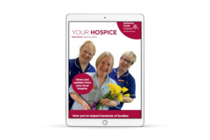 Your Hospice spring 2023 newsletter front cover shown on an iPad. The cover features three nurses smiling at the camera; one is holding a bunch of daffodils.