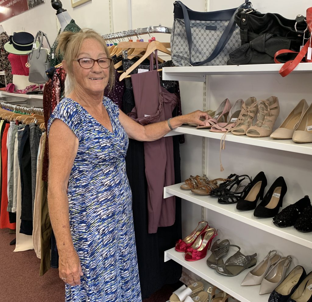 Volunteer Susan standing next to shelves of shoes in the Eccleshall shop