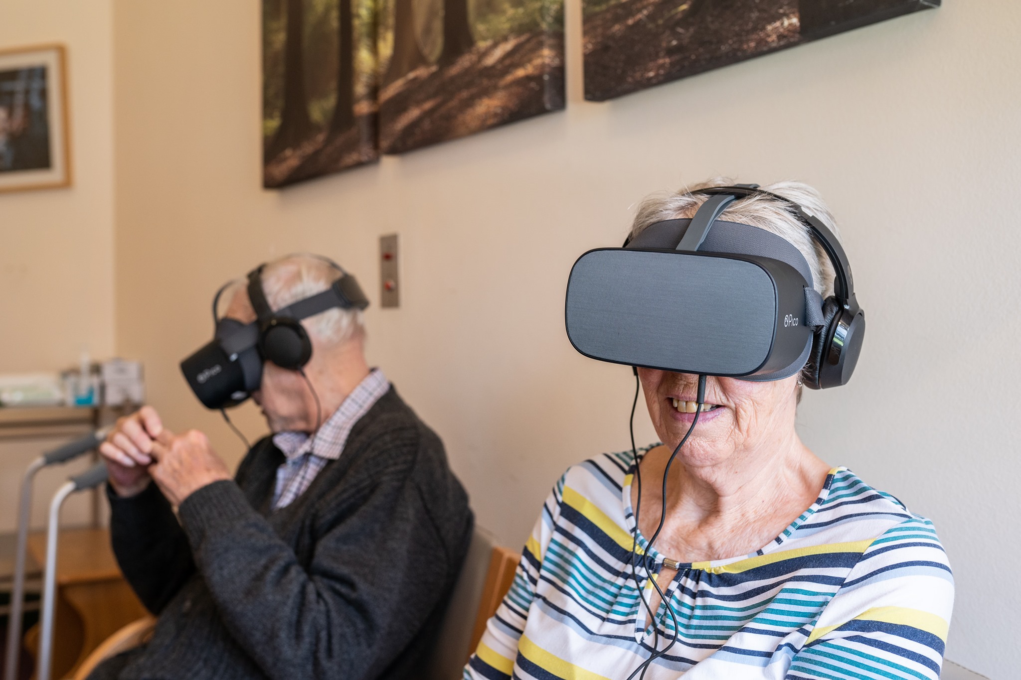 A man and woman seated in a room swearing VR headsets,