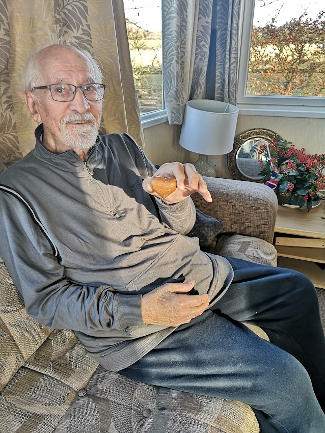 Ivan sat on a sofa holding a wooden heart in his hand