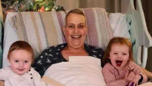 Marie laughs with her young grandchildren on her bed in the hospice.