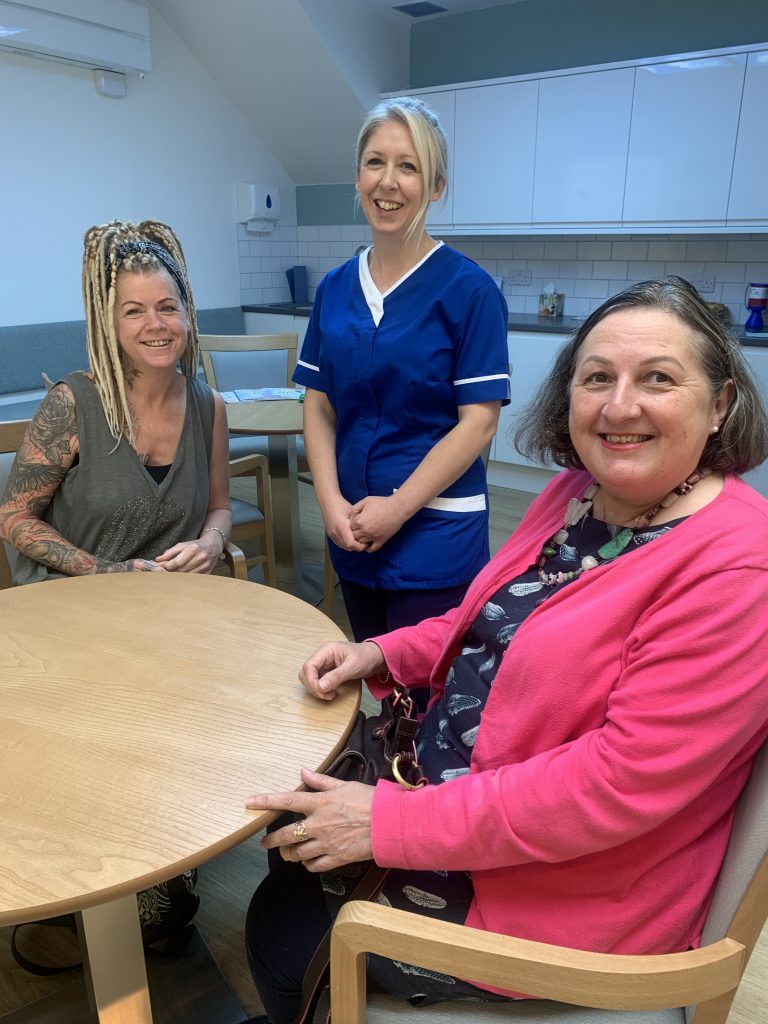 A nurse stands alongside two patients