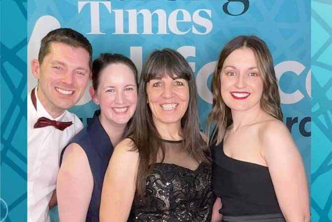 Four people in black tie have a photo in a Nursing Times selfie frame.