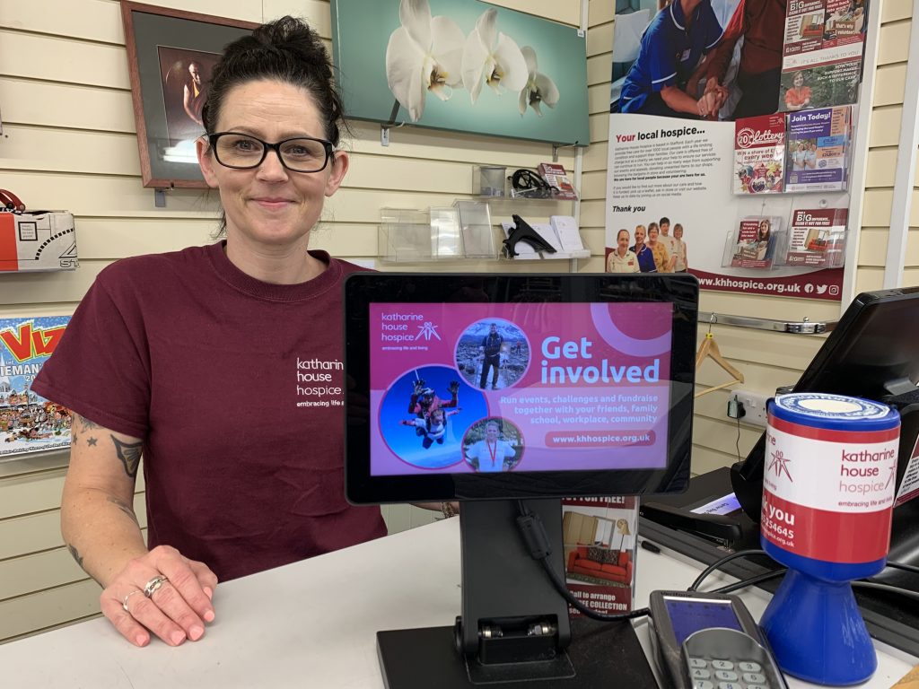 A staff member behind a till with a picture display in front of her