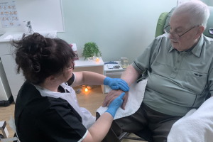 Man seated in chair receiving treatment from a professional complementary therapist.