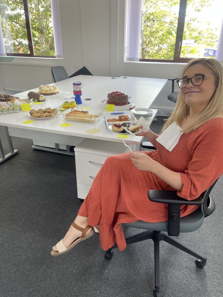 A woman sat smiling beside a table of baked treats