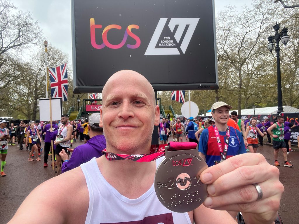 James smiling after the London Marathon with his medal