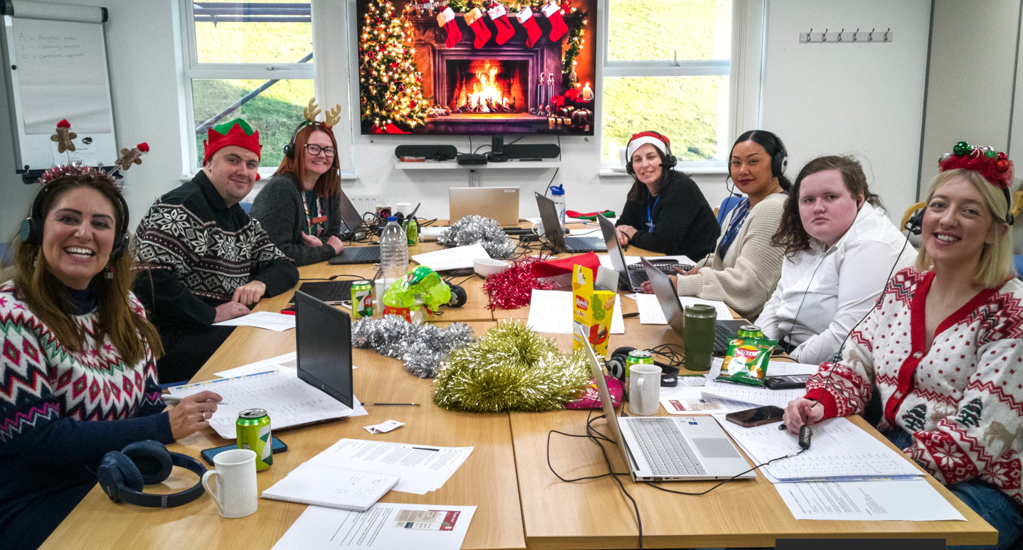 The telemarketing team and Katharine House staff sat around a large desk about to make phone calls.