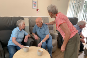 A patient and carer chatting to a volunteer.