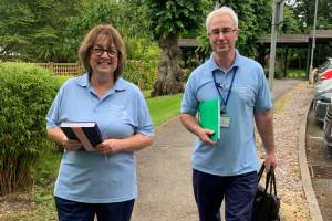 Two Hospice at Home staff leaving the hospice to visit a patient. Equipped with bags and folders.