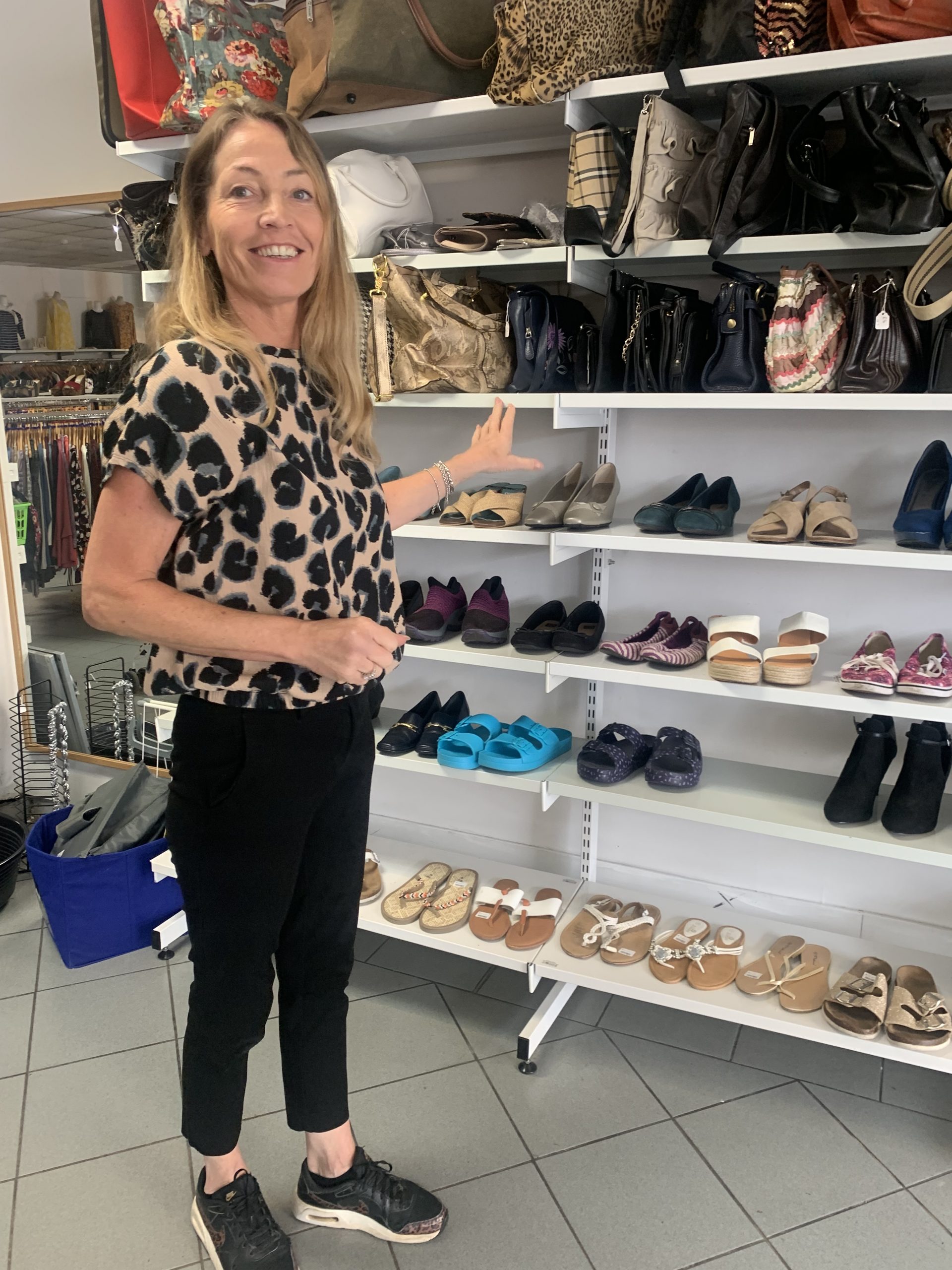 Stoke Deputy Manager, Jane, smiles to the camera while organising a shelf.