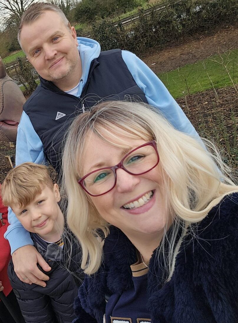 Mel taking a selfie with her two young sons and her husband at a dinosaur park