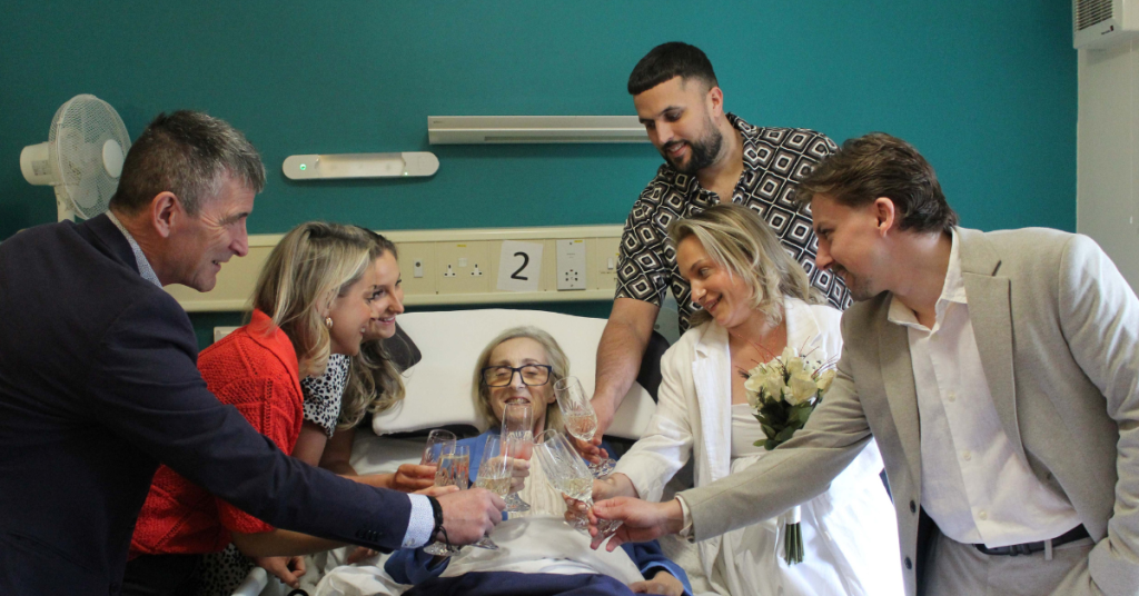 A family gather around a mum's bedside raising glasses