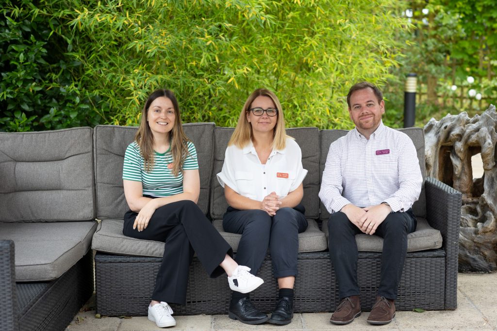 Our Family Support Team (L-R: Hannah, Deb and Javier) sitting together outside smiling to camera.