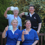 Care for a Cuppa 35 Nurses 300x300 Four female uniformed healthcare workers smiling at the camera and holding up cups of tea.