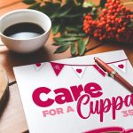 Photo of a printed welcome pack for an event called Care for a Cuppa 35. A pen is placed on top of the paper and a cup of coffee is next to it.