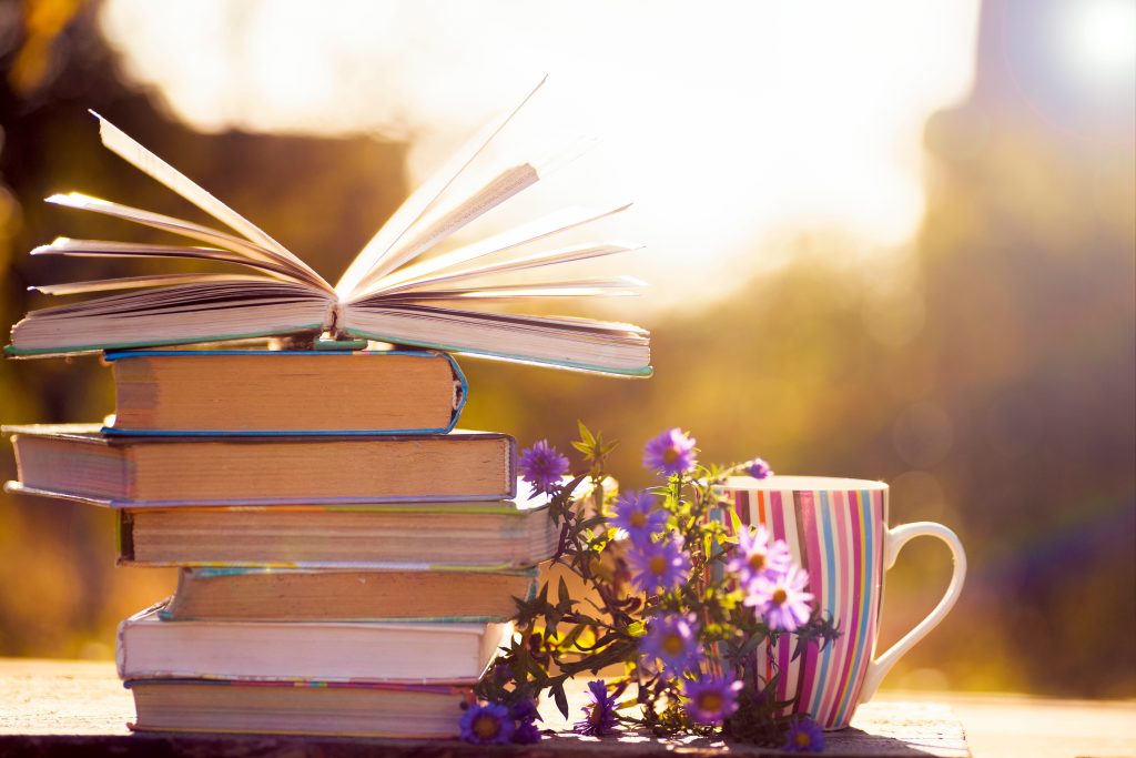 Open book on wooden table on natural background. Toned image. Soft focus