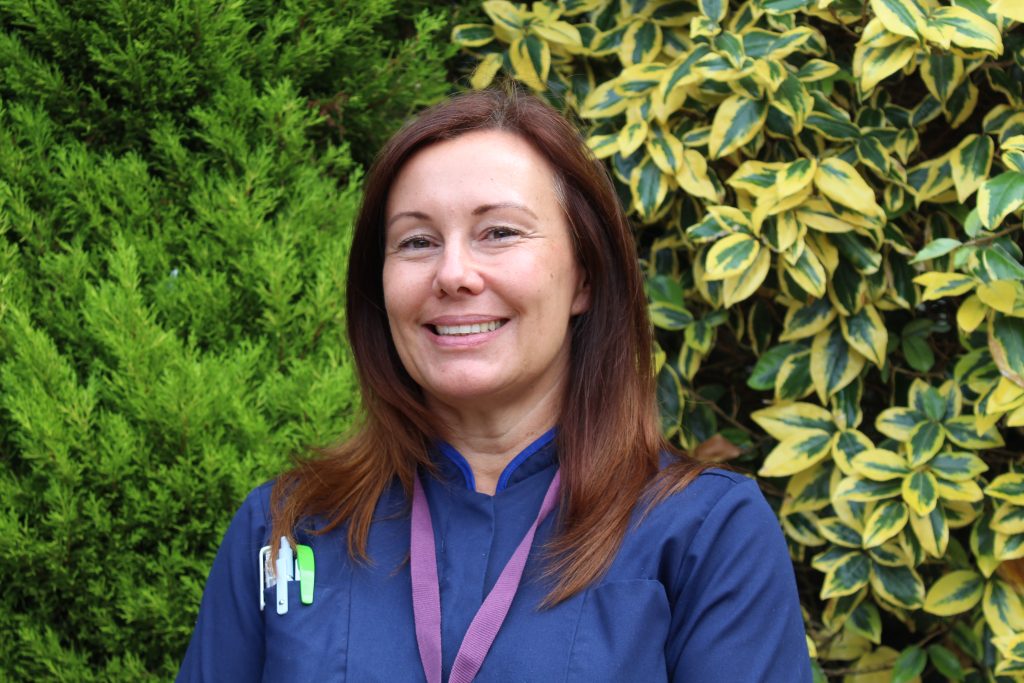 Woman in nurses uniform, smiling in a garden setting
