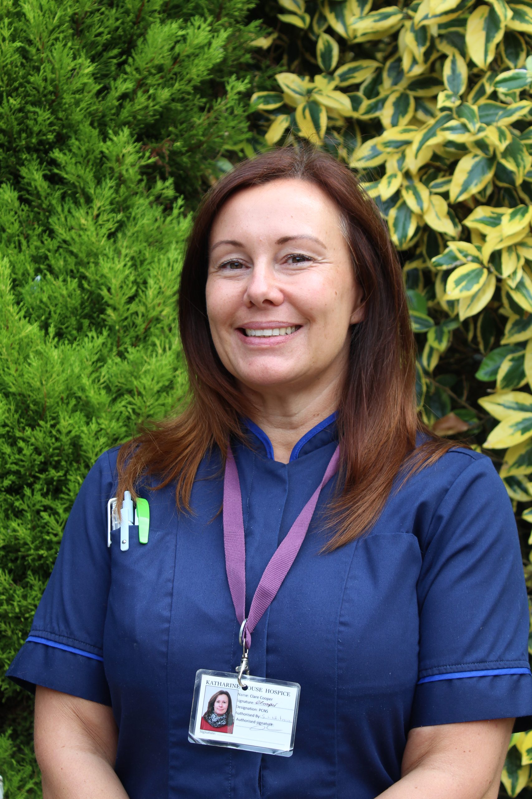 Woman in nurses uniform, smiling, in hospice garden setting