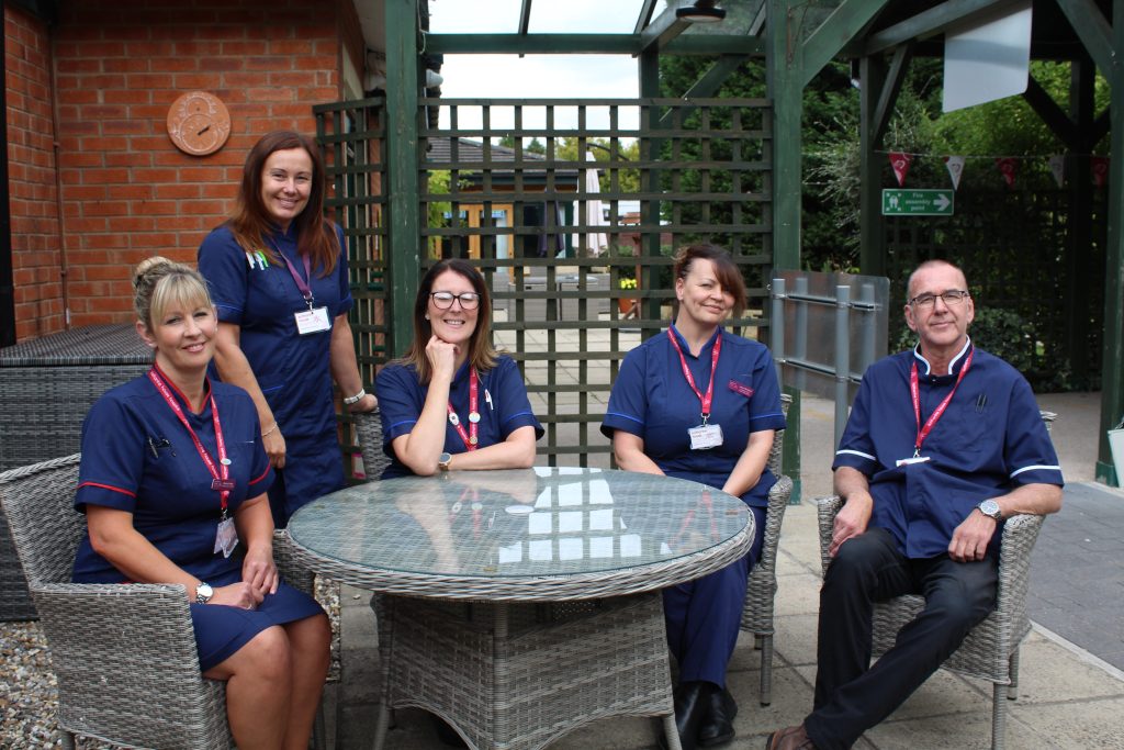 Mixed group of female and male nurses sat together in the hospice garden