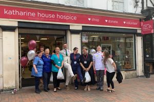 Charles Hanson and staff with their shopping People outside the shop front. Five are in nurses uniform and Charles Hanson is in the middle. They are laughing and kicking their legs out.