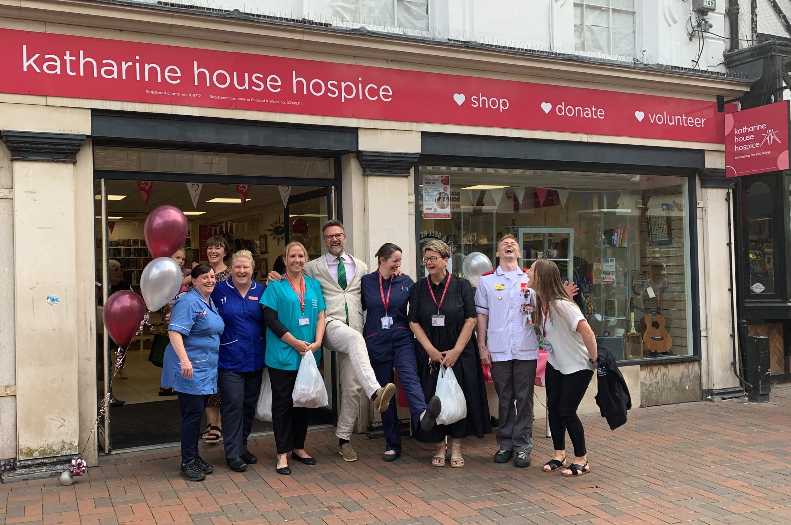 Charles Hanson and staff with their shopping People outside the shop front. Five are in nurses uniform and Charles Hanson is in the middle. They are laughing and kicking their legs out.