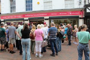 The crowd starting to gather ahead of the opening A crowd of people outside the shop front all facing away from the camera as they wait for the shop to open.