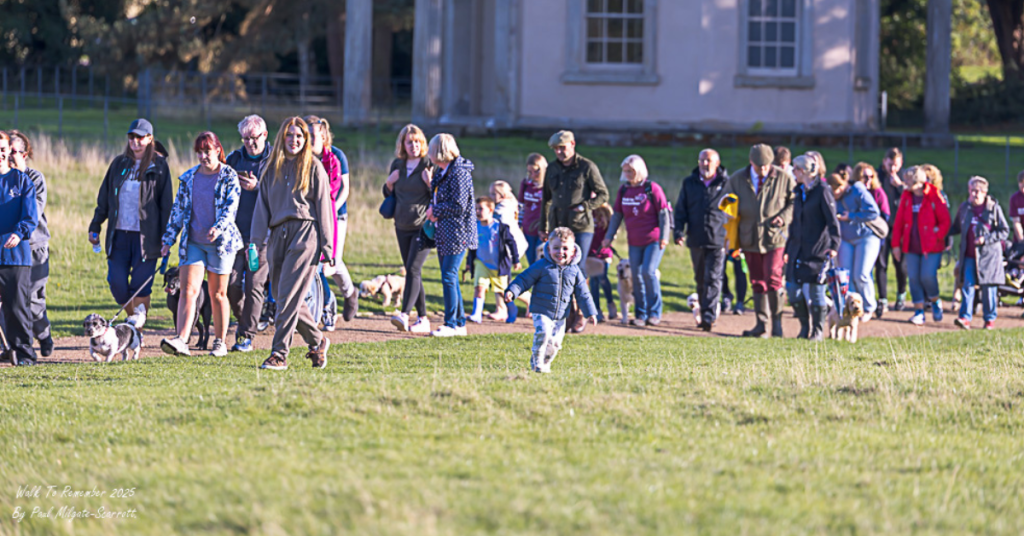 A group of 20 people of all ages walking along a path