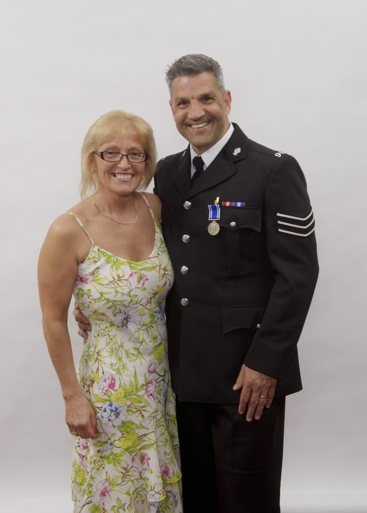 Adrian and Gaynor Naik 2 A man in police uniform stands arm in arm with a woman in a summer dress.