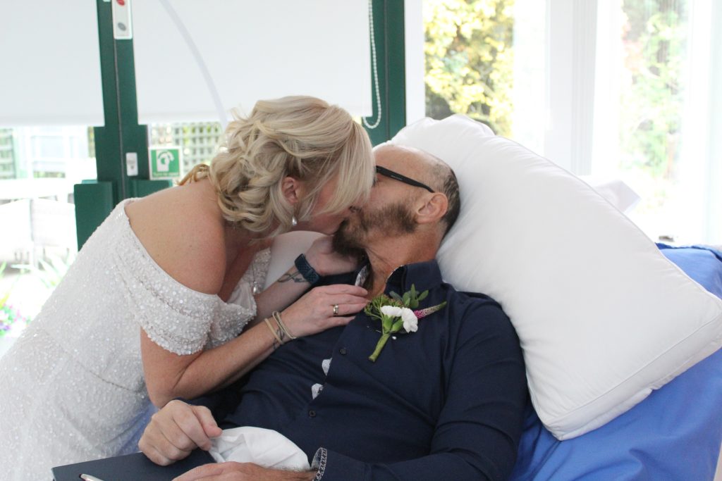 Sarah and Karl A blonde lady in wedding dress kissing a man in a dark shirt.
