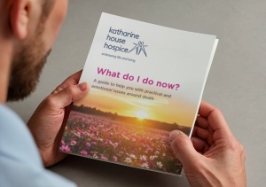 A person reading a booklet from Katharine House Hospice titled 'what do i do now?'