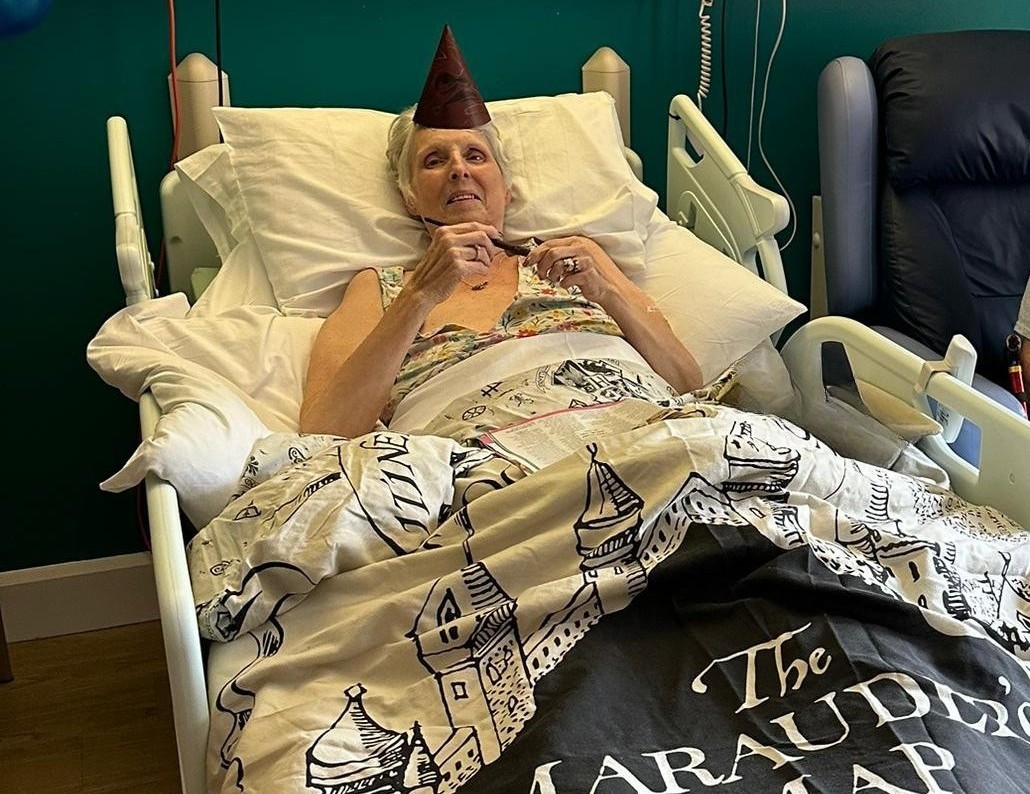 A woman lies in bed smiling, with a Harry Potter duvet and decorations around her.