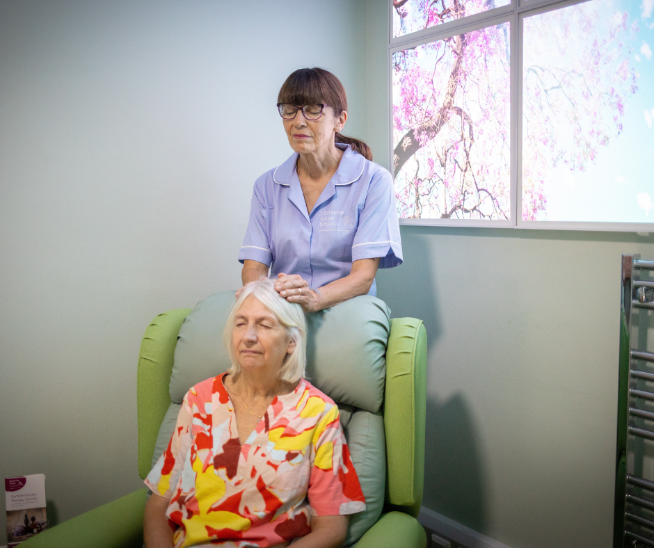 A woman gives Reiki therapy to a patient, in a calm therapy room.