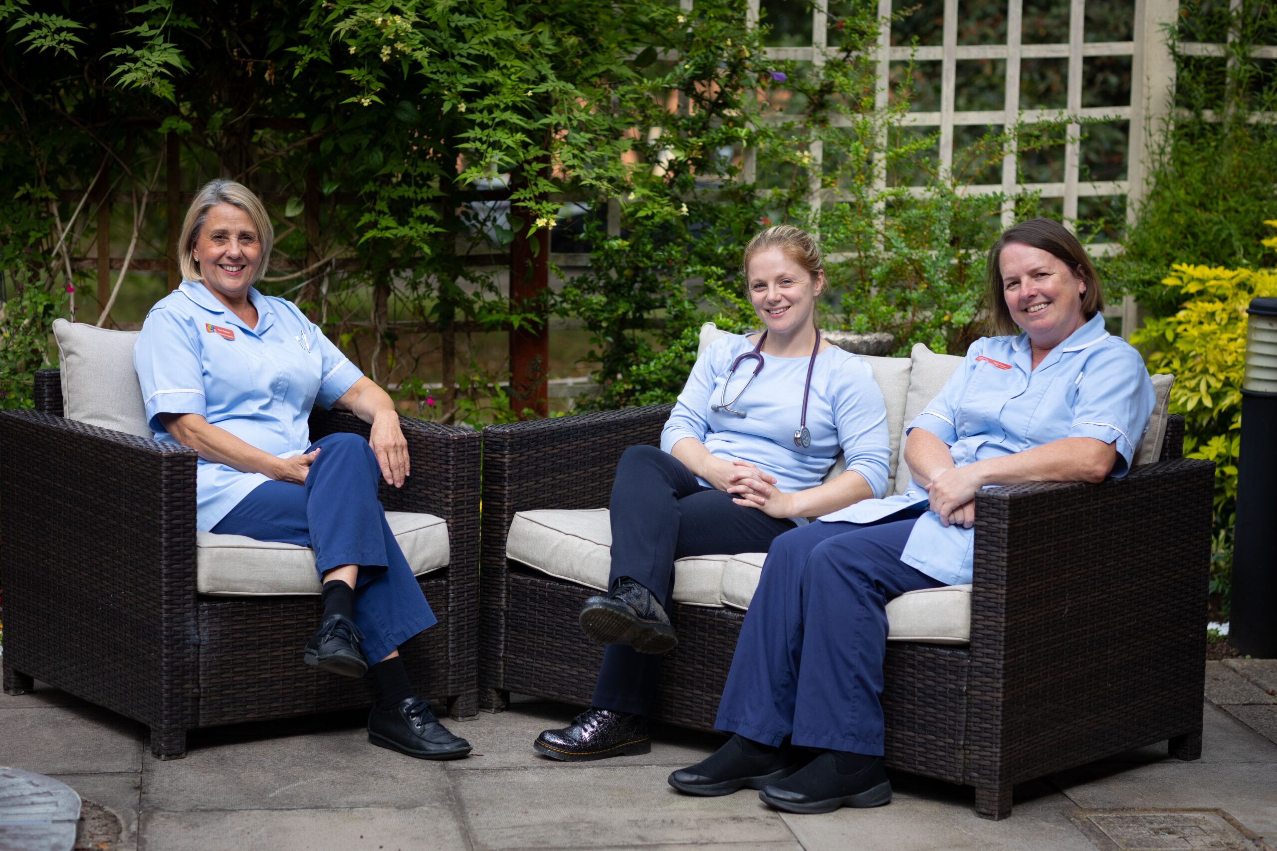 Two nurses and a doctor sat outside in the garden.