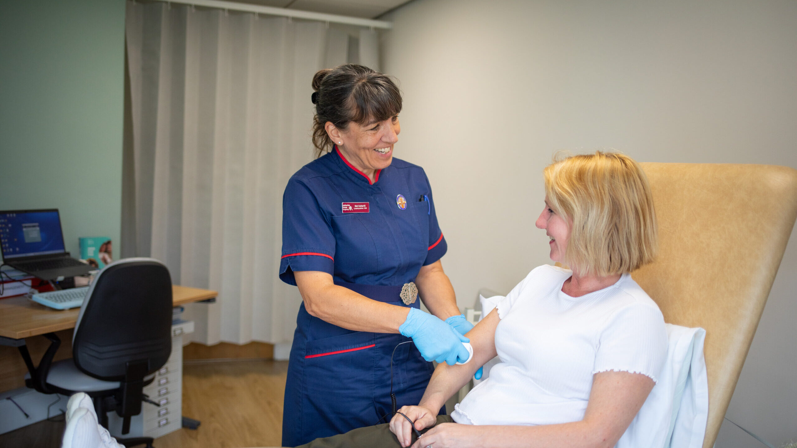 A nurse giving laser treatment on the arm of a patient.