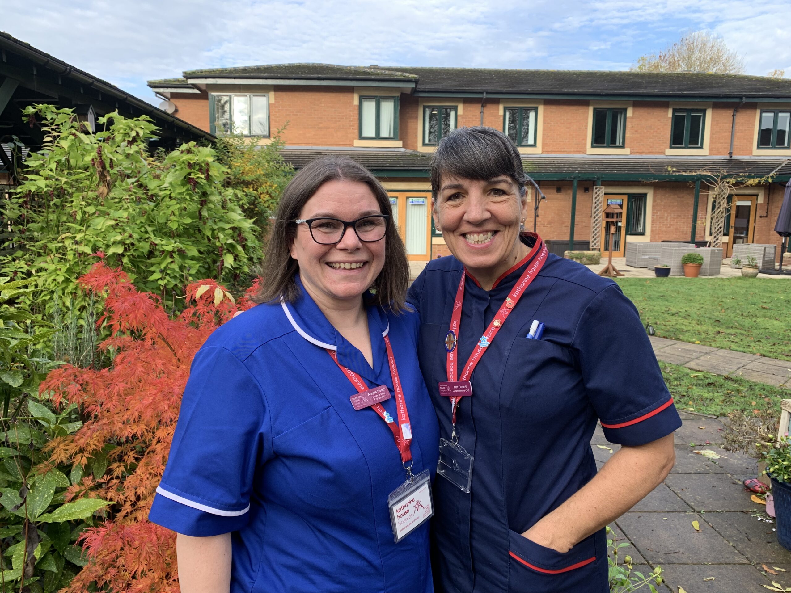 Two nurses smiling to camera with their arms around each other.