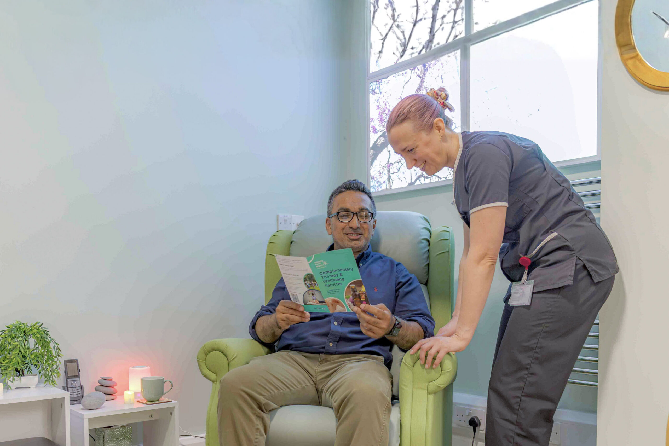 A man reads a leaflet, guided by a therapist.