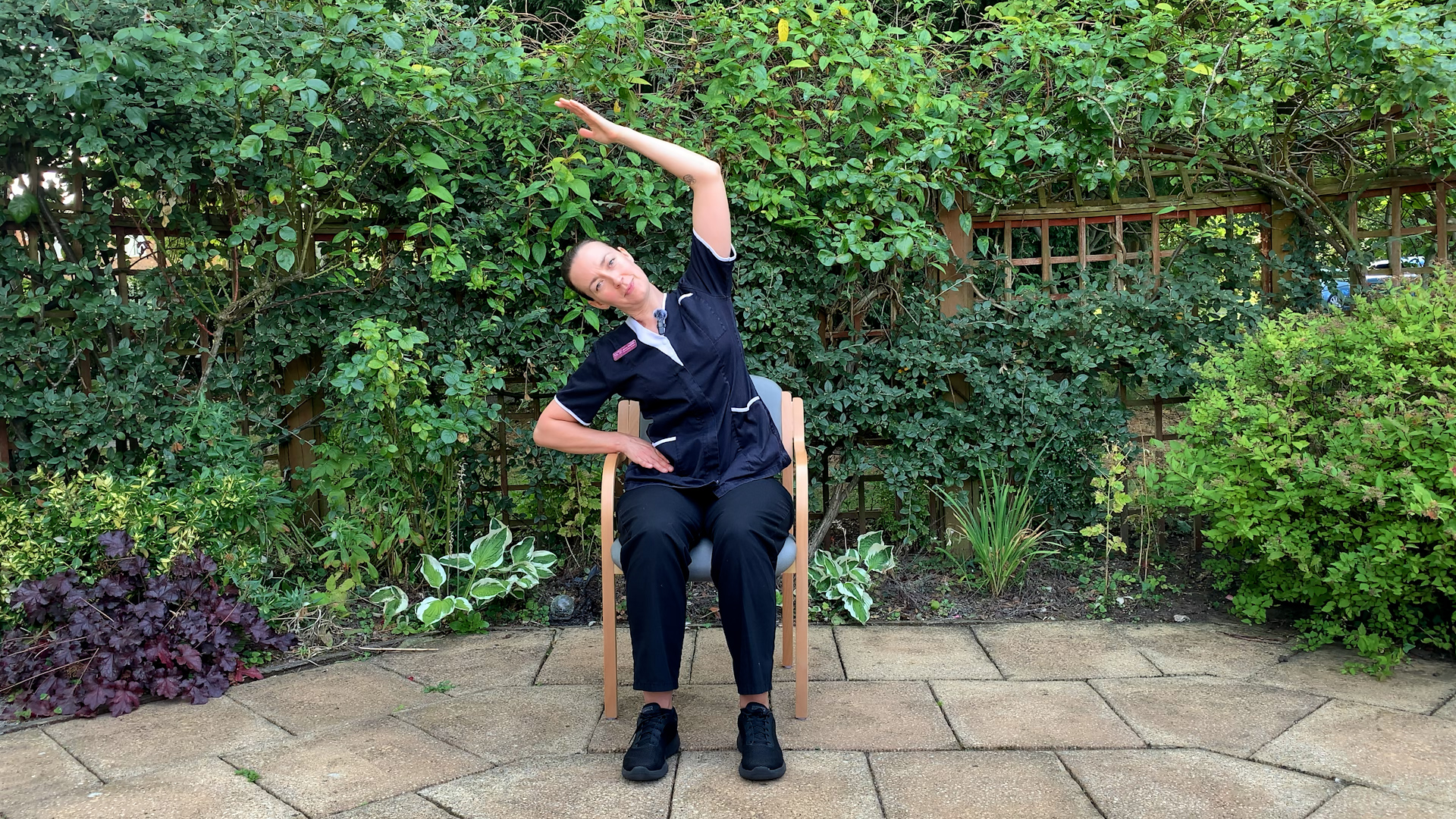 A woman stretching while sitting on a chair.
