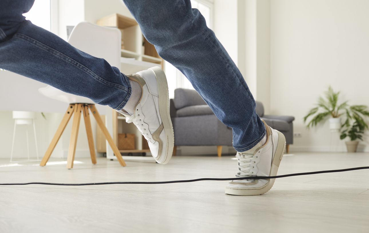 Close up of feet. Person falls down after stumbling over a power cable.