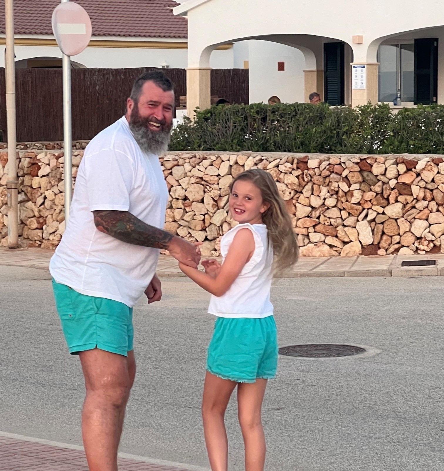 Father and young daughter on holiday in matching outfits.