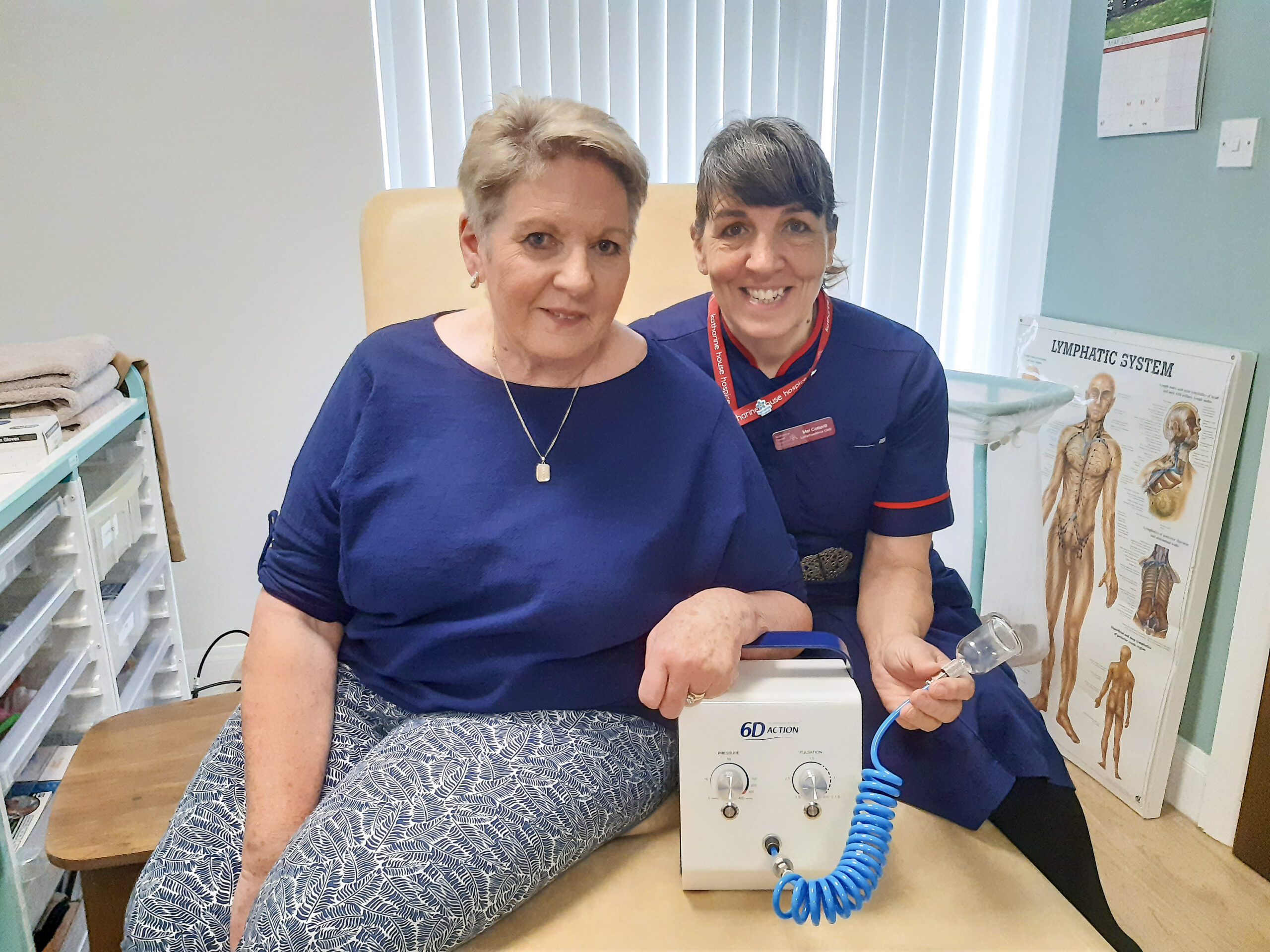 A woman and therapist sit on a bed, showing off the cupping therapy machine.